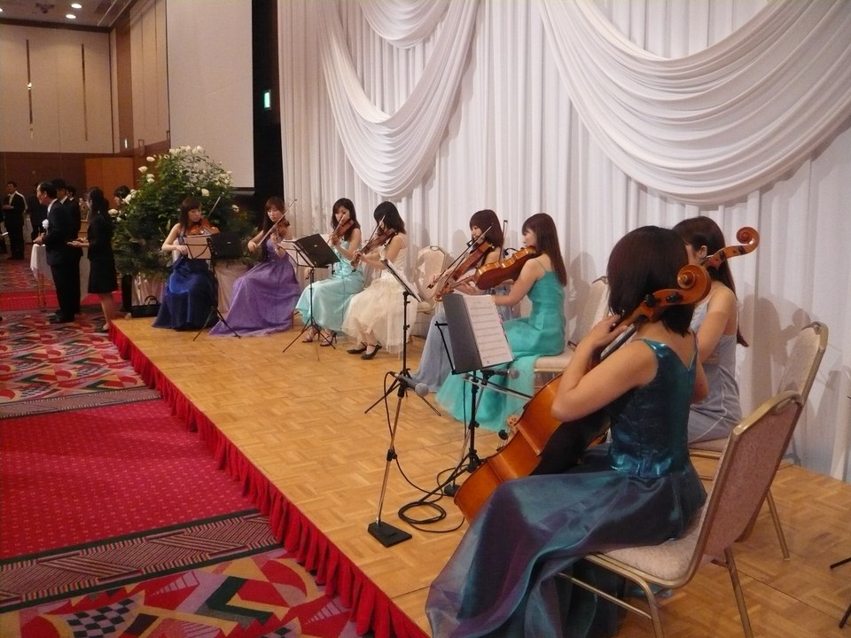 ホテル宴会場でドレス姿で演奏する弦楽アンサンブル