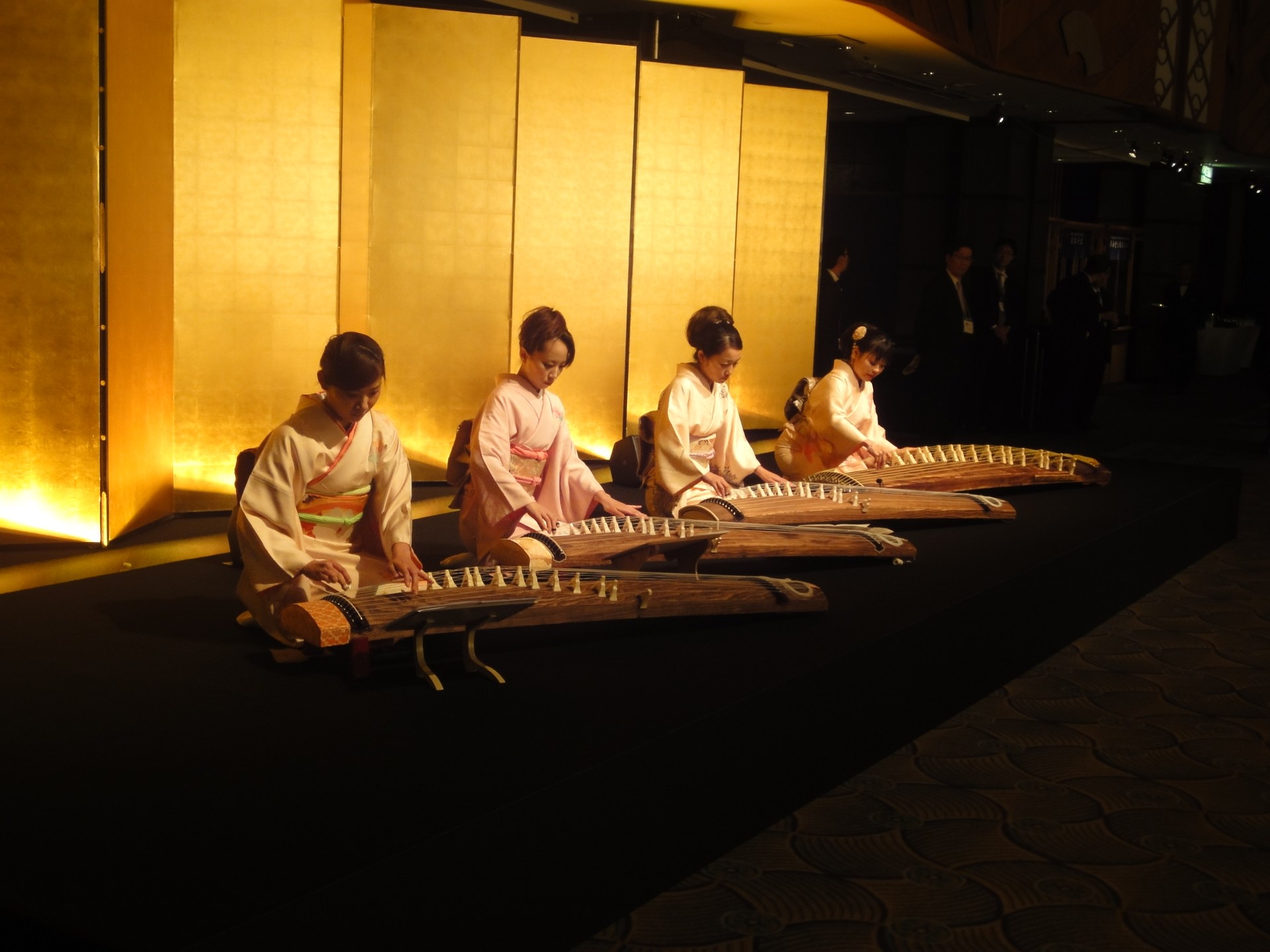 金屏風の前で着物姿の4名が箏を演奏するアンサンブル