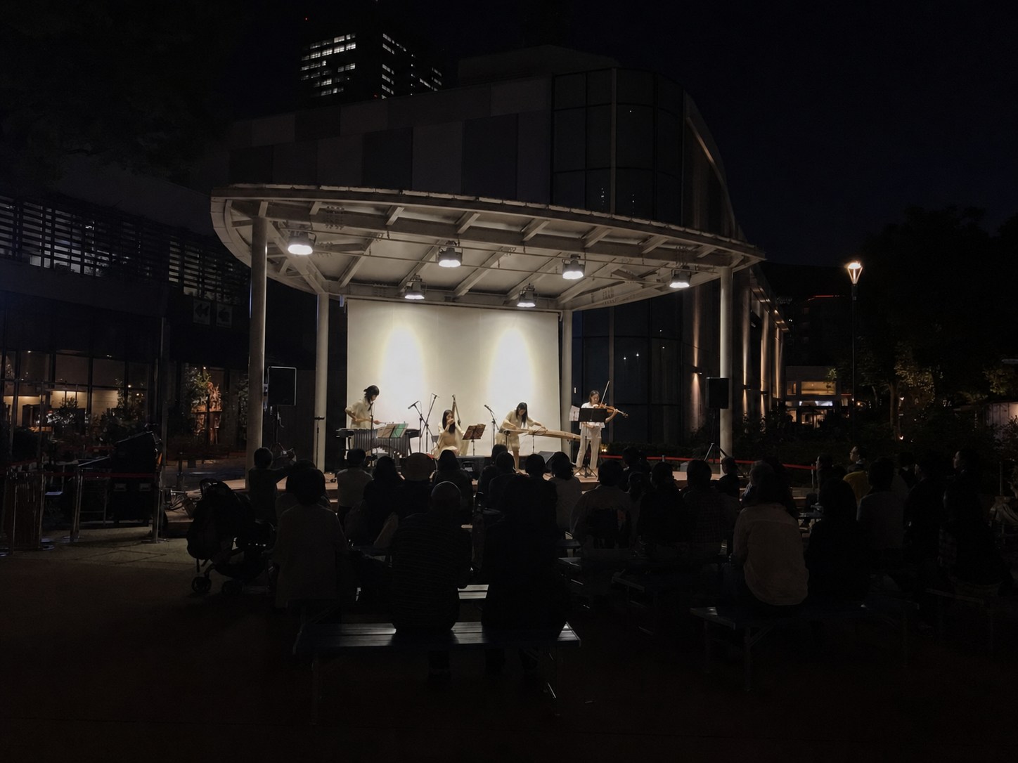 夜の屋外ステージで和楽器とヴァイオリン、パーカッションを演奏するユニット